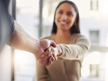 Focused image of a handshake with female blurred in background