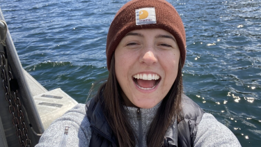 Self image of young woman with brown hair, wearing a toque with a big smile.